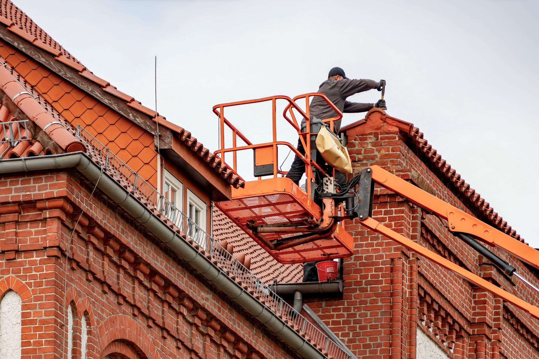 Dakwerker in een hoogwerker aan de nok van een pannendak